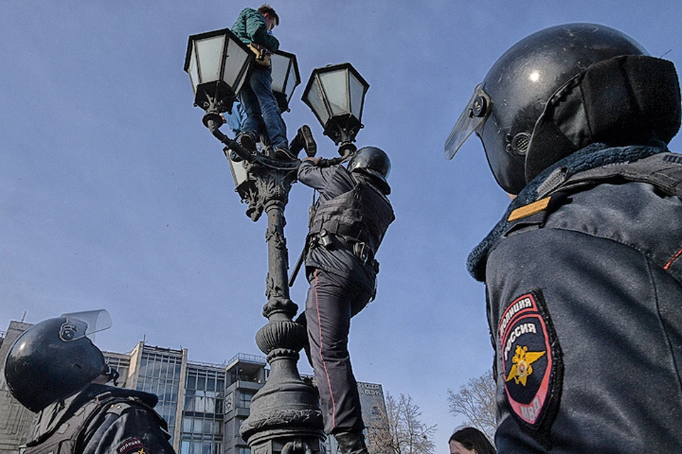 26 марта 2017 года, Москва. Полицейский пытается стащить участника несанкционированного митинга с фонаря на Пушкинской площади.