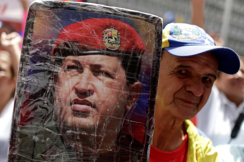 Сторонник президента Мадуро с портретом его предшественника - Уго Чавеса.