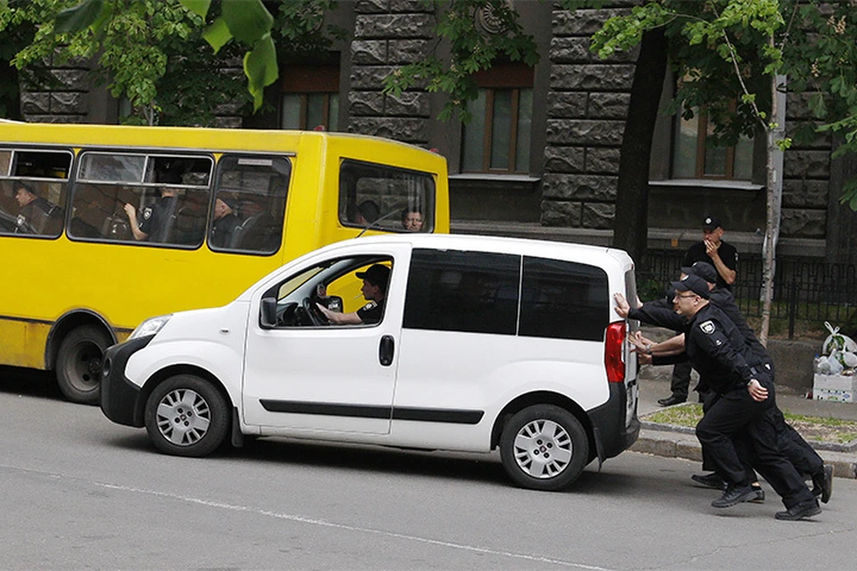 Украинские полицейские толкают свой автомобиль в центре Киева.