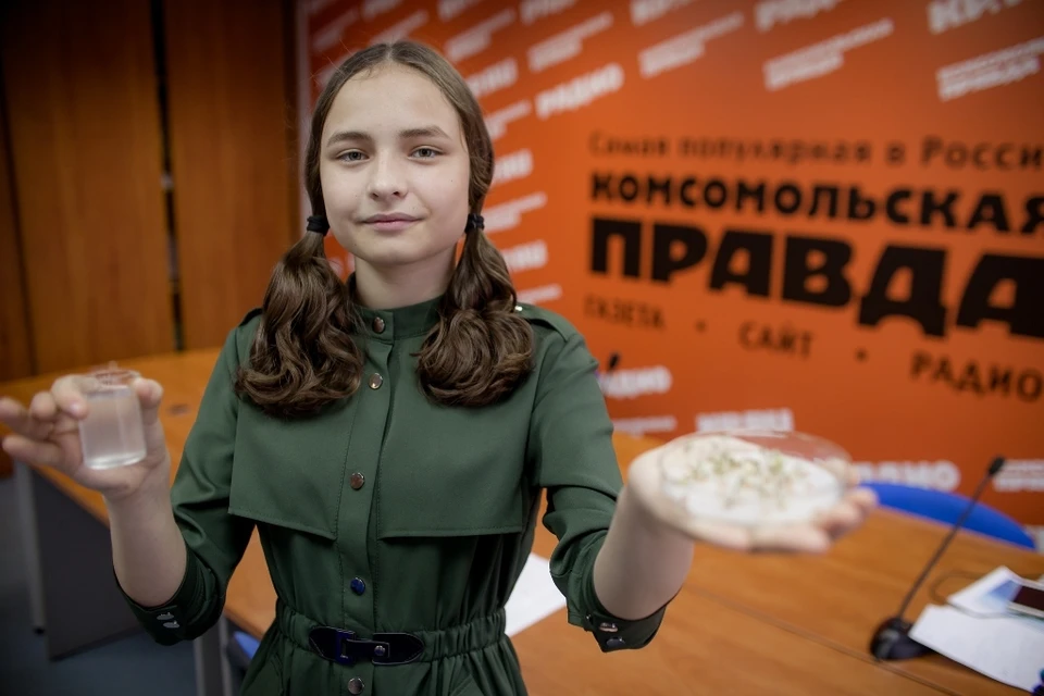 Татьяна Махмутова держит стаканчик с дафниями и блюдце с кресс-салатом.