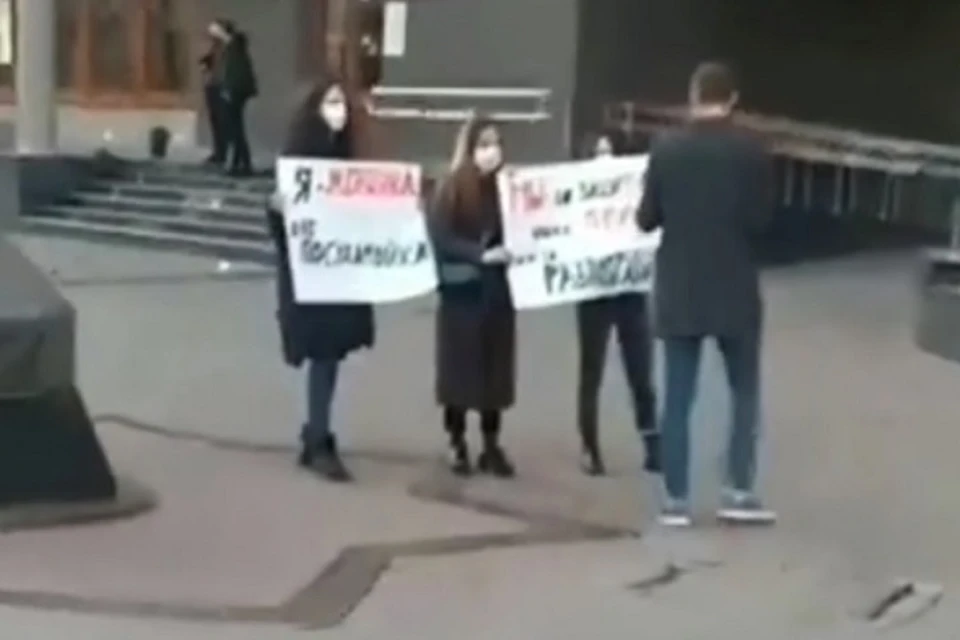 Девушки с плакатами зачем-то скрывали свои лица за медицинскими масками.