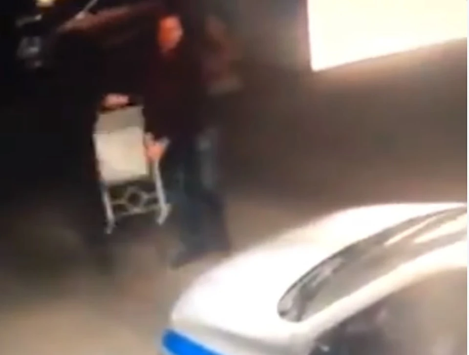 На одной из парковок разбушевавшийся мужчина запустил в машину полиции урну. Скриншот видео.