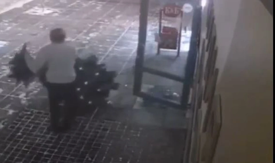 В Тюмени парень выломал дверь салона красоты и унес елку. Скриншот из видео.