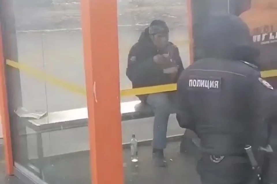 Мужчина пьет и закусывает на остановке транспорта во Владивостоке. Скриншот видео из соцсетей Интернет