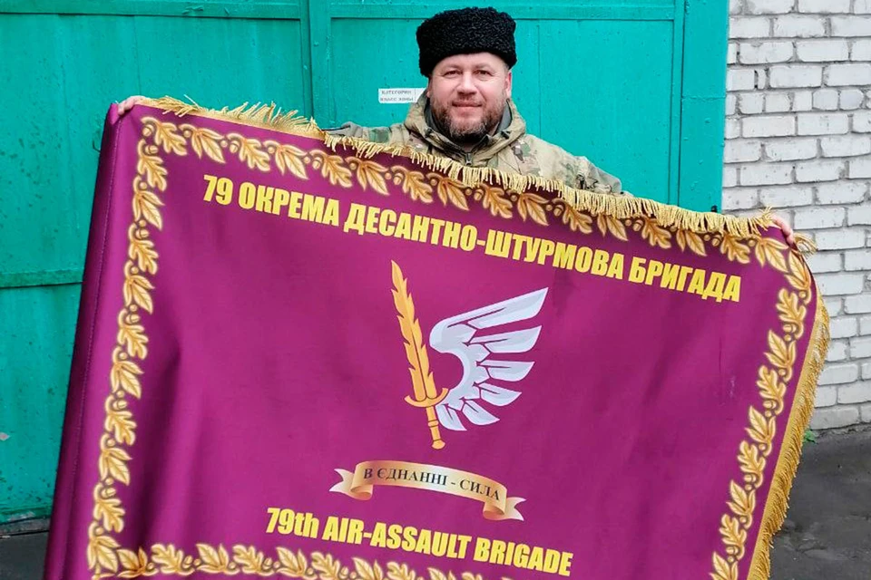 Российский казак демонстрирует боевое знамя украинских националистов, которое они бросили.