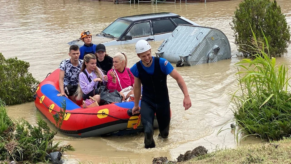 Спасатели помогают туристам перебраться через улицы полные воды