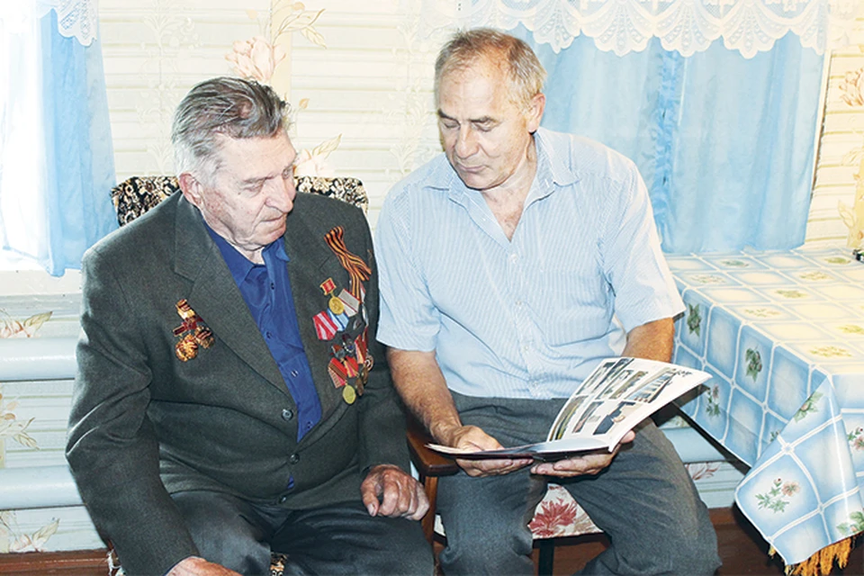 Глава села Виктор Засенко показывает Алексею Стародубцеву книгу, изданную к юбилею района