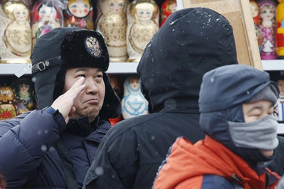 Китайский турист выбирает себе сувенир в Москве.