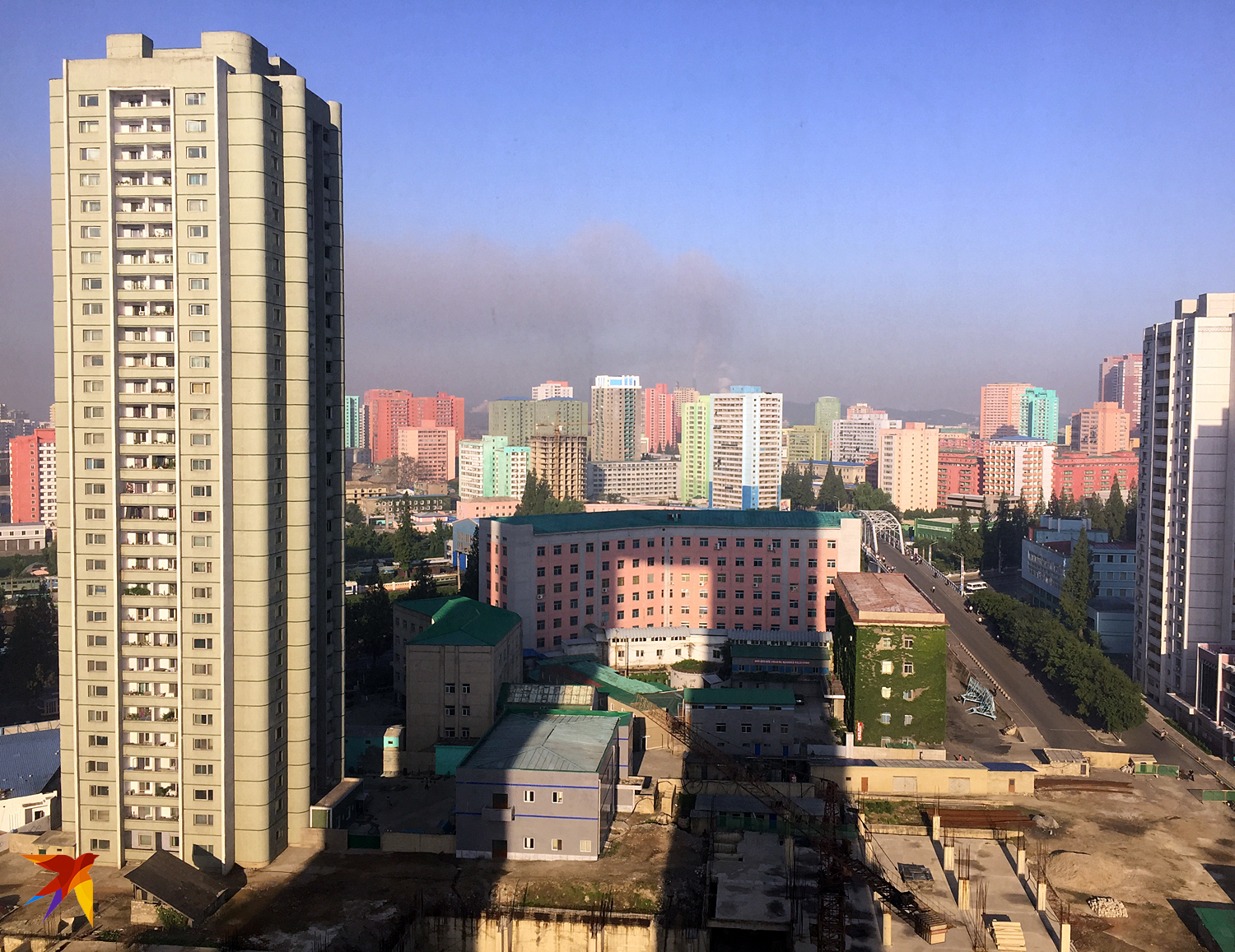 В Пхеньяне куда ни глянь, всюду стройка. Такие разноцветные дома стали появляться в Пхеньяне несколько лет назад. До этого весь город был из мрачного серого бетона