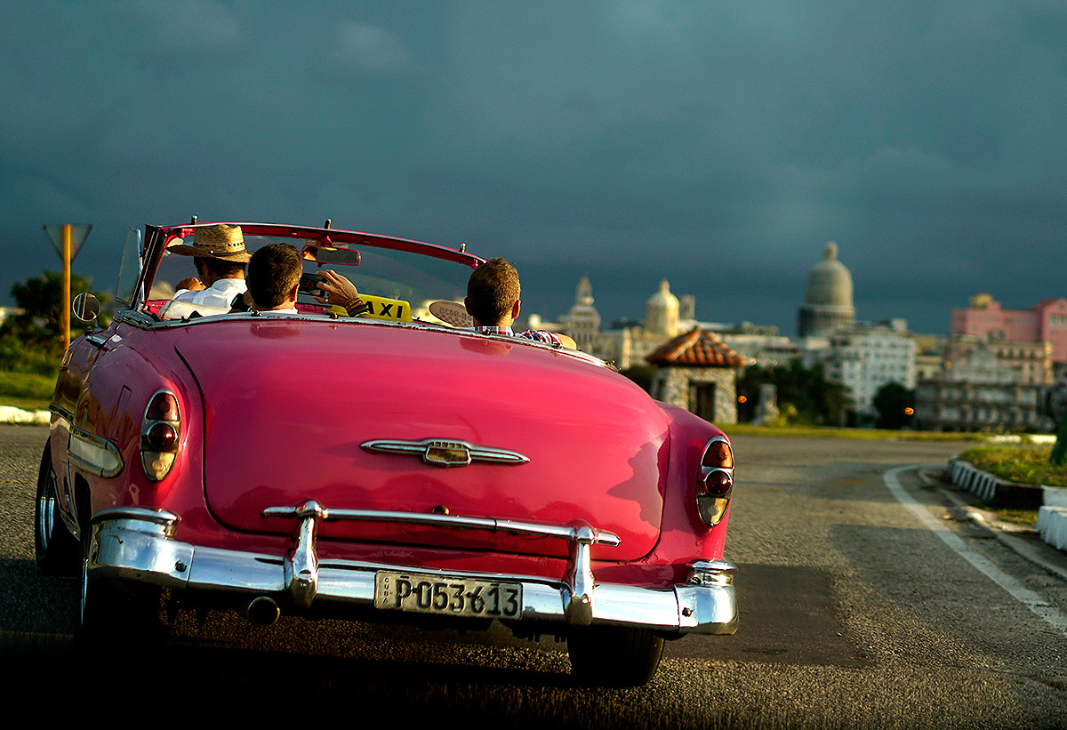 Классическое американское авто с туристами на борту на улицах Гаваны.